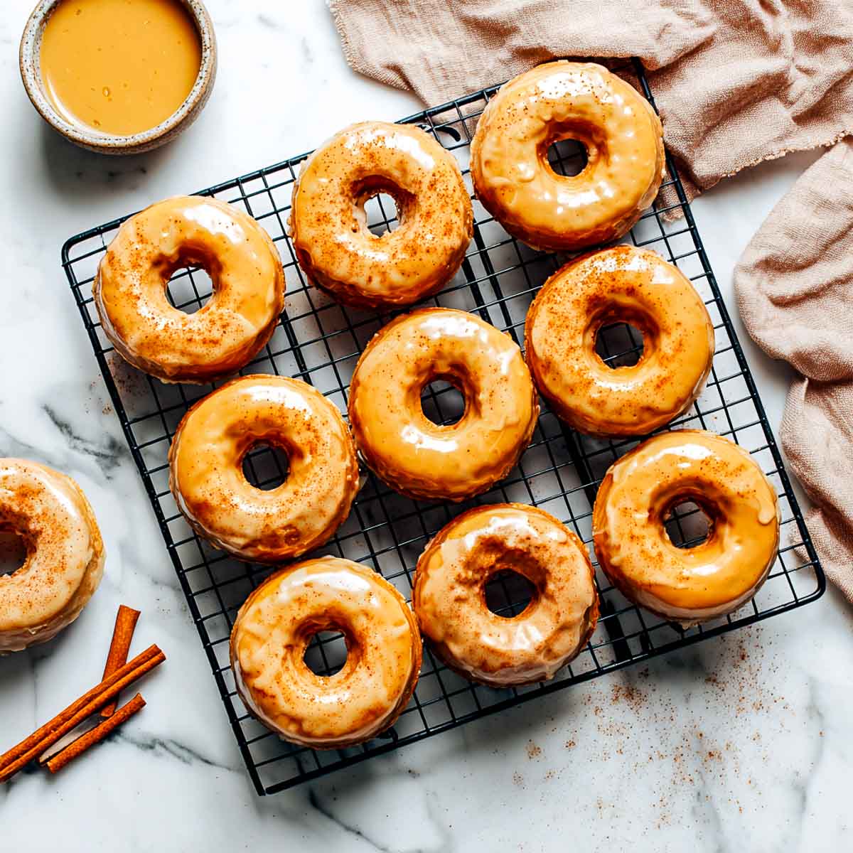 Maple glazed vegan donuts with pumpkin spice on a wire rack.
