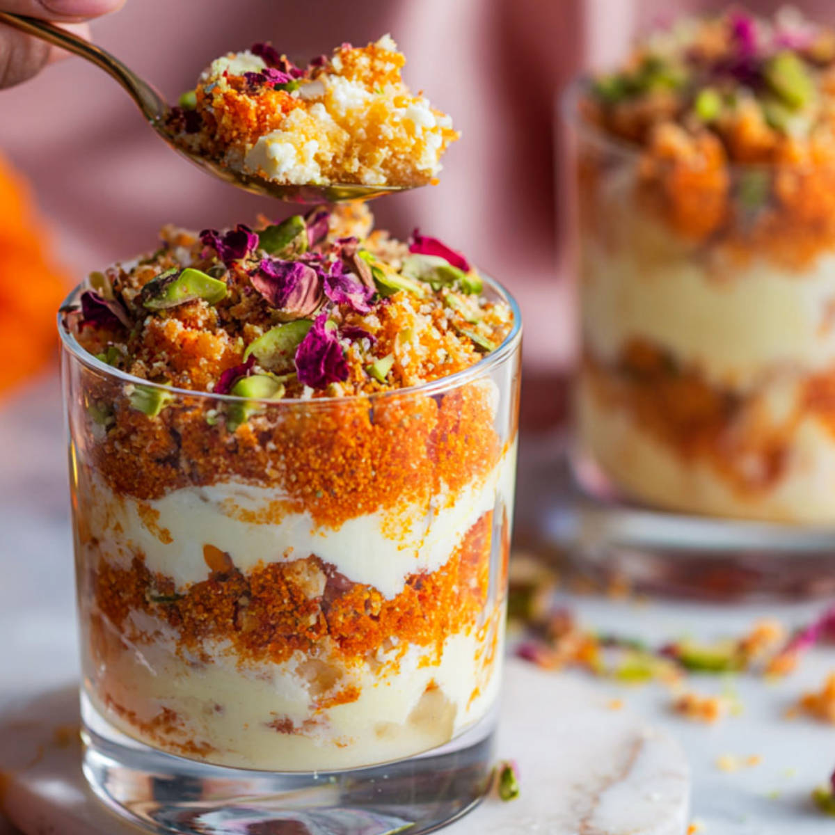 Close-up of motichoor ladoo cheesecake shots garnished with pistachios and rose petals.