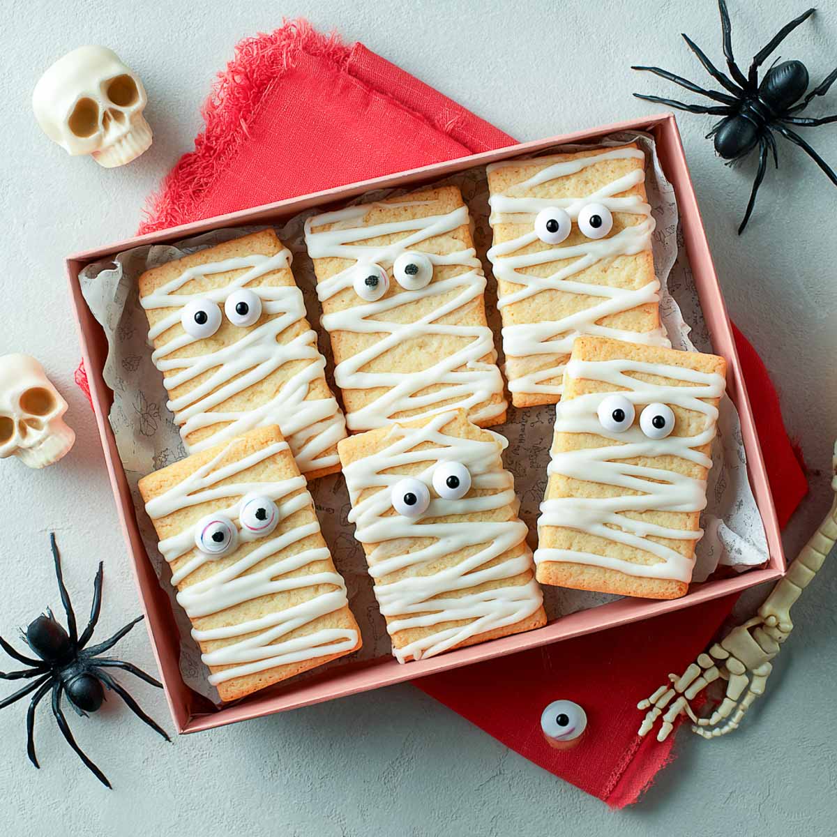 Box of mummy Halloween cookies decorated with white icing and eyes.