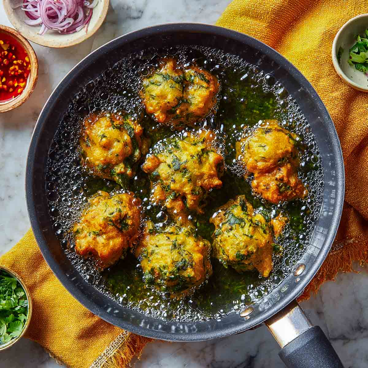 Palak pakoras frying in hot oil until golden and crisp.