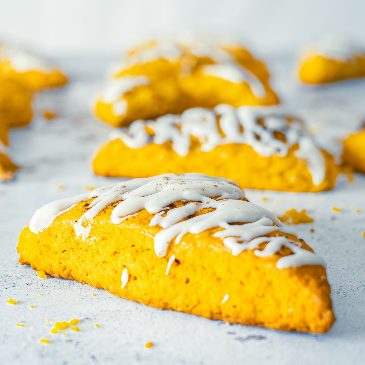 Close-up of a pumpkin spice scone topped with vanilla glaze drizzle.