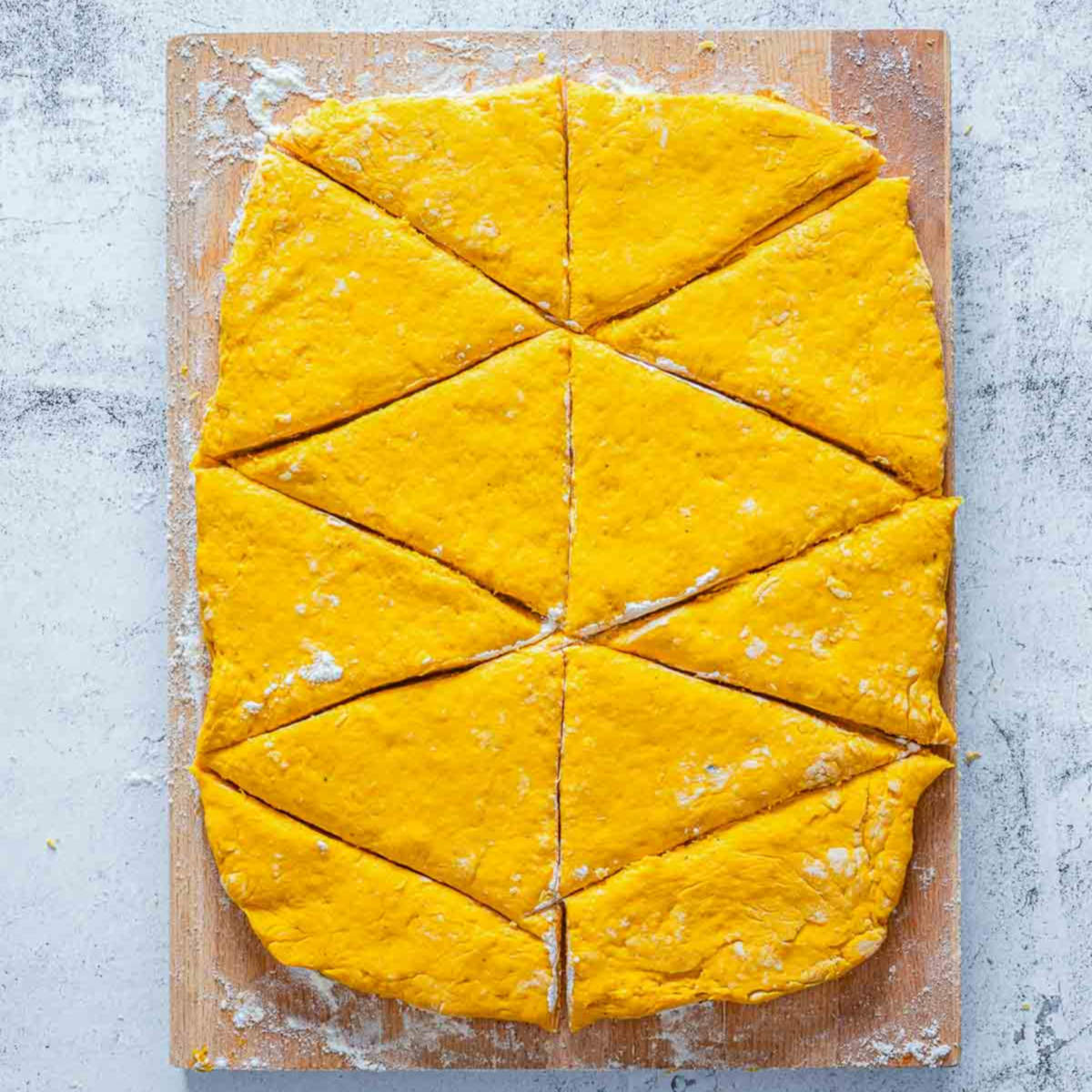Pumpkin scone dough rolled out and cut into triangle wedges on board.