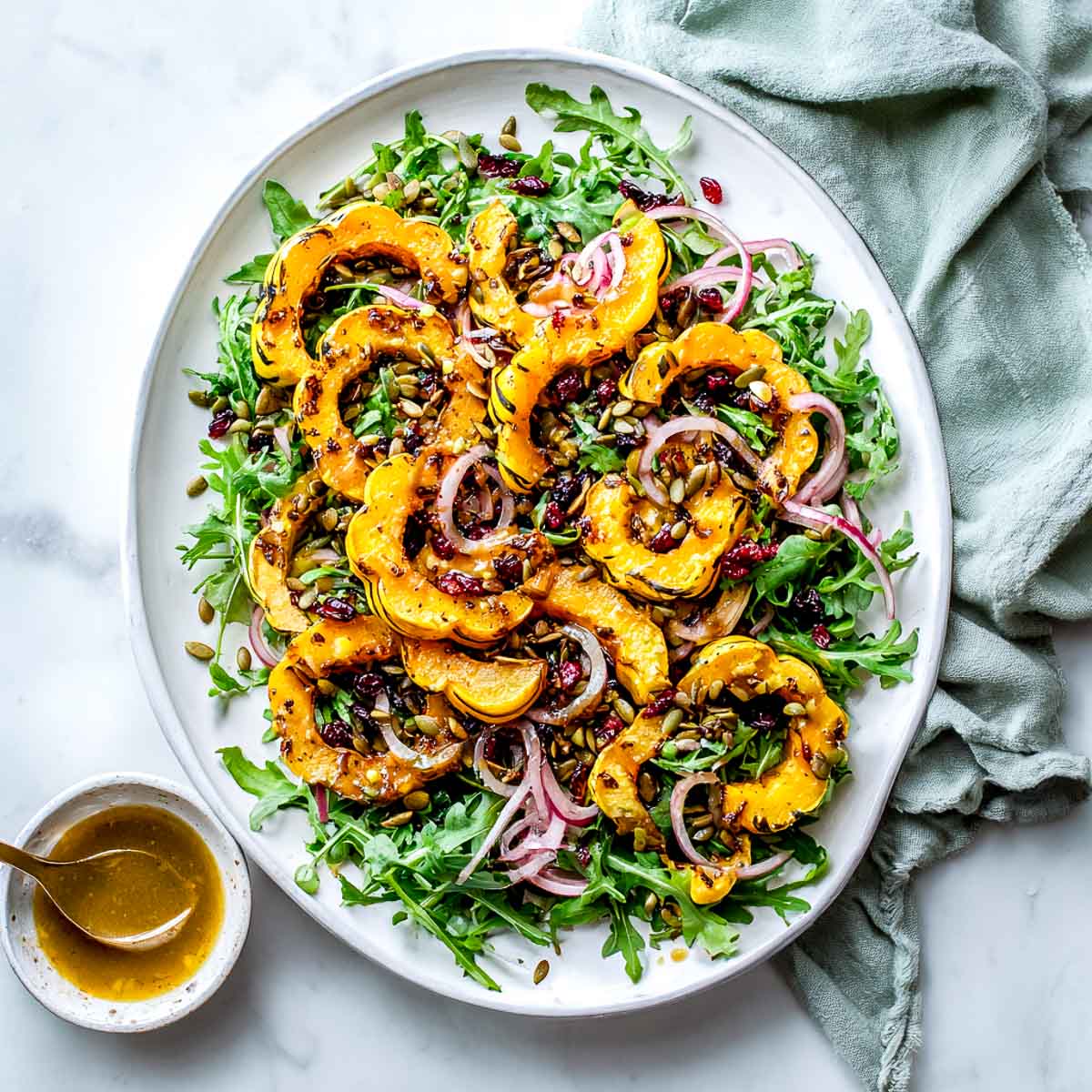 Roasted delicata squash salad with arugula, cranberries, pumpkin seeds, and maple Dijon dressing.