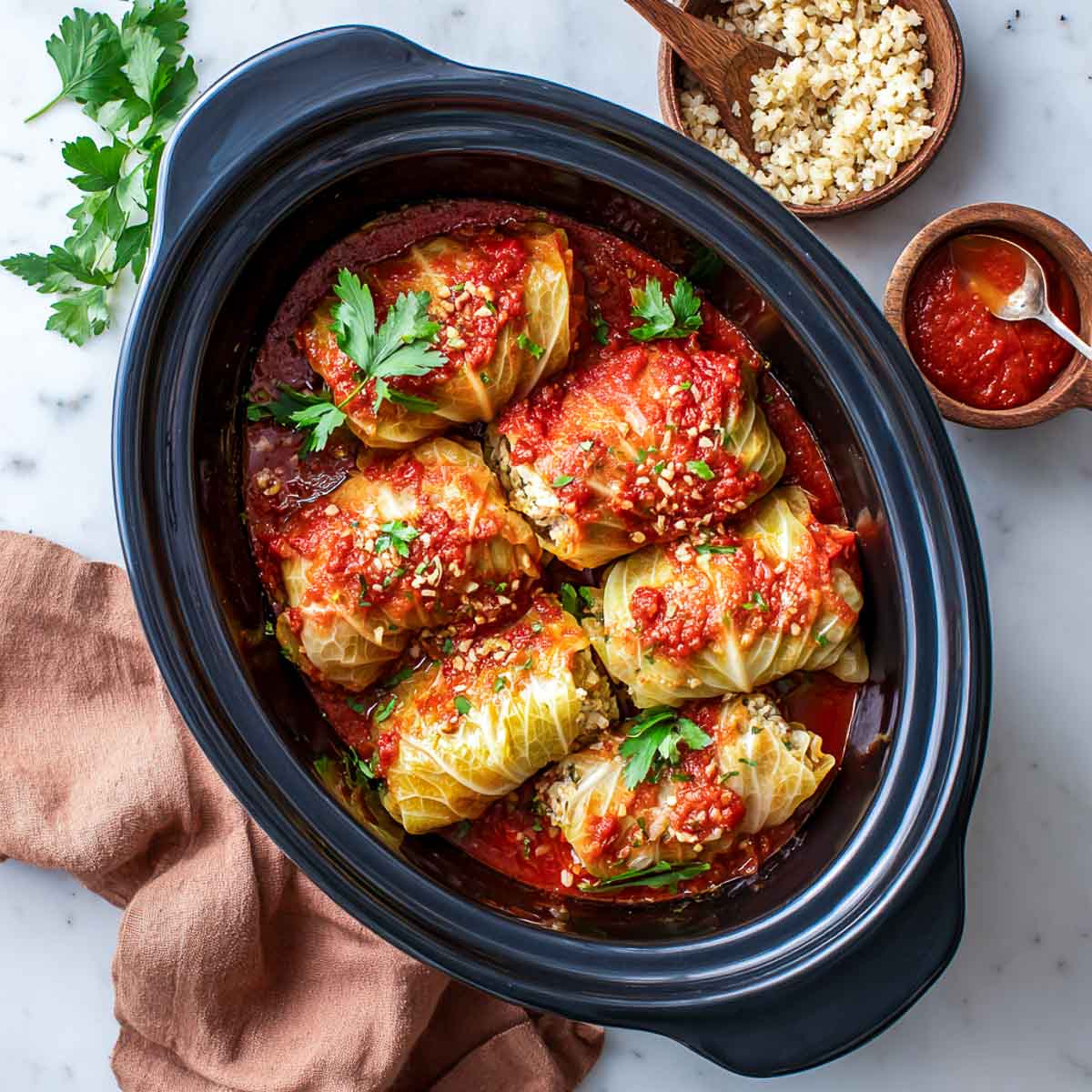 Stuffed cabbage rolls with tomato sauce and fresh parsley in a crockpot.