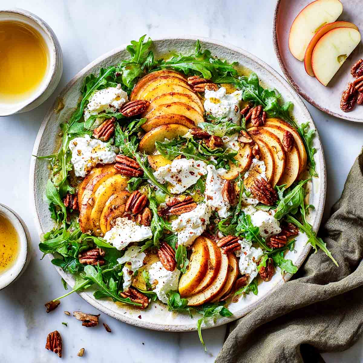 Sliced spiced apples with arugula, vegan cottage cheese, and pecans.