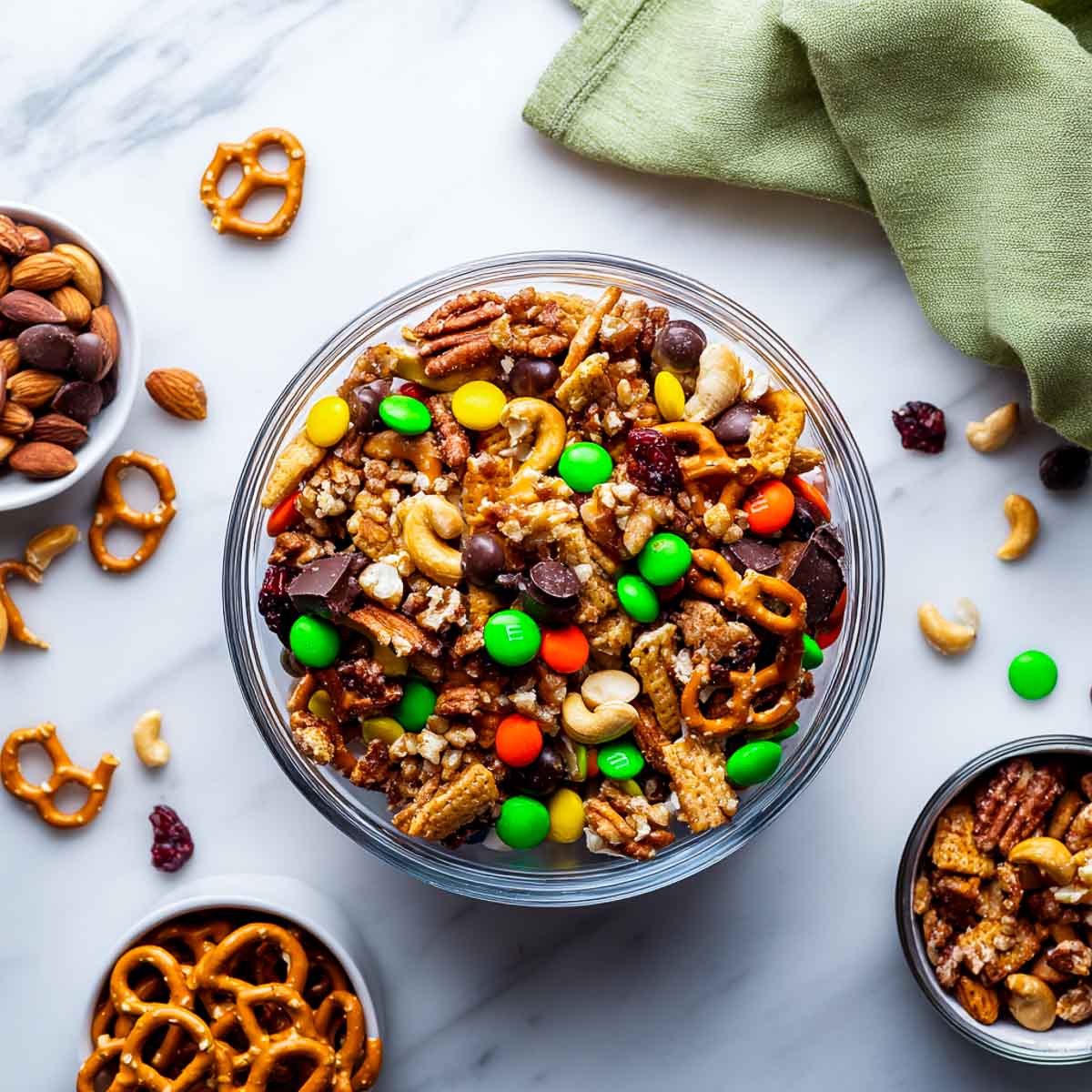 Bowl of trail mix with nuts, pretzels, and colorful Halloween candies.