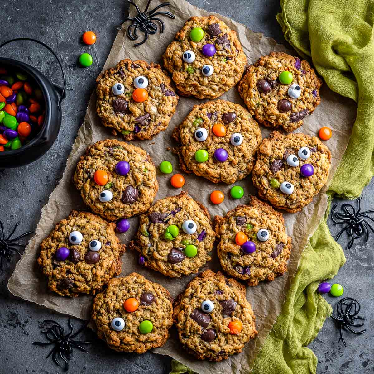 Top-down view of vegan monster cookies with candy eyes and colorful candies.