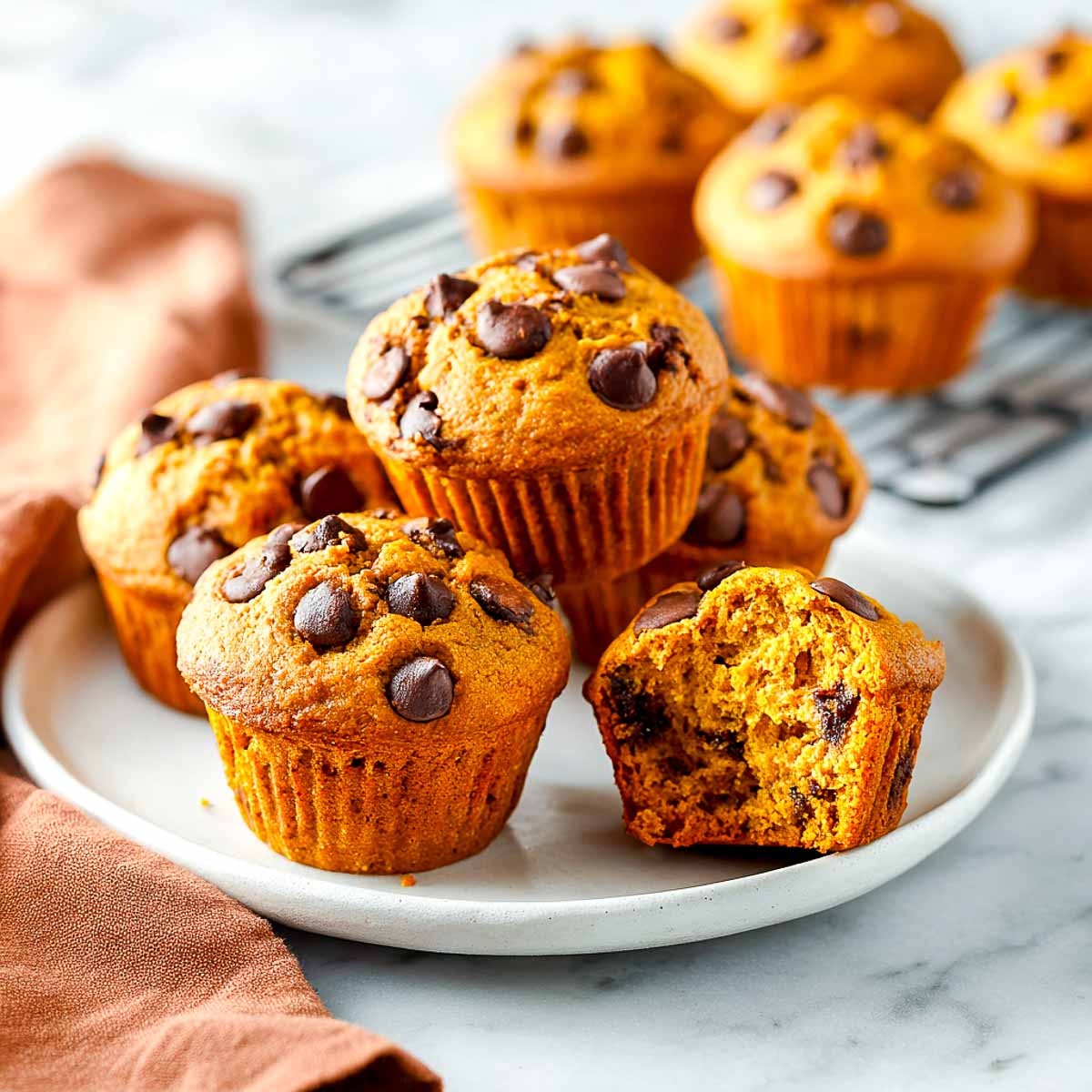 Pumpkin chocolate chip muffins with fluffy orange crumb and melted chocolate.