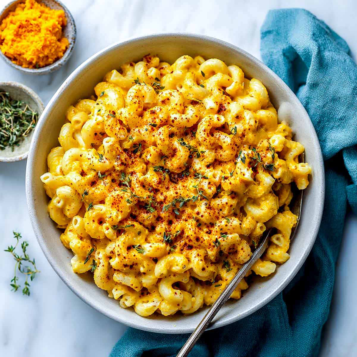 Bowl of vegan pumpkin mac and cheese with paprika and thyme garnish.