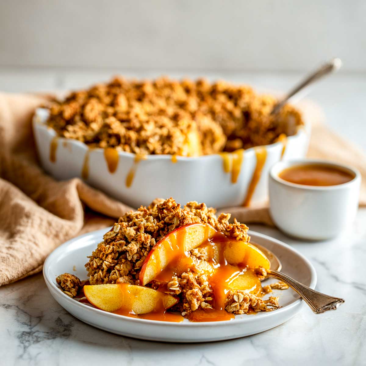 Vegan salted caramel apple crisp served with warm caramel drizzle on a plate.