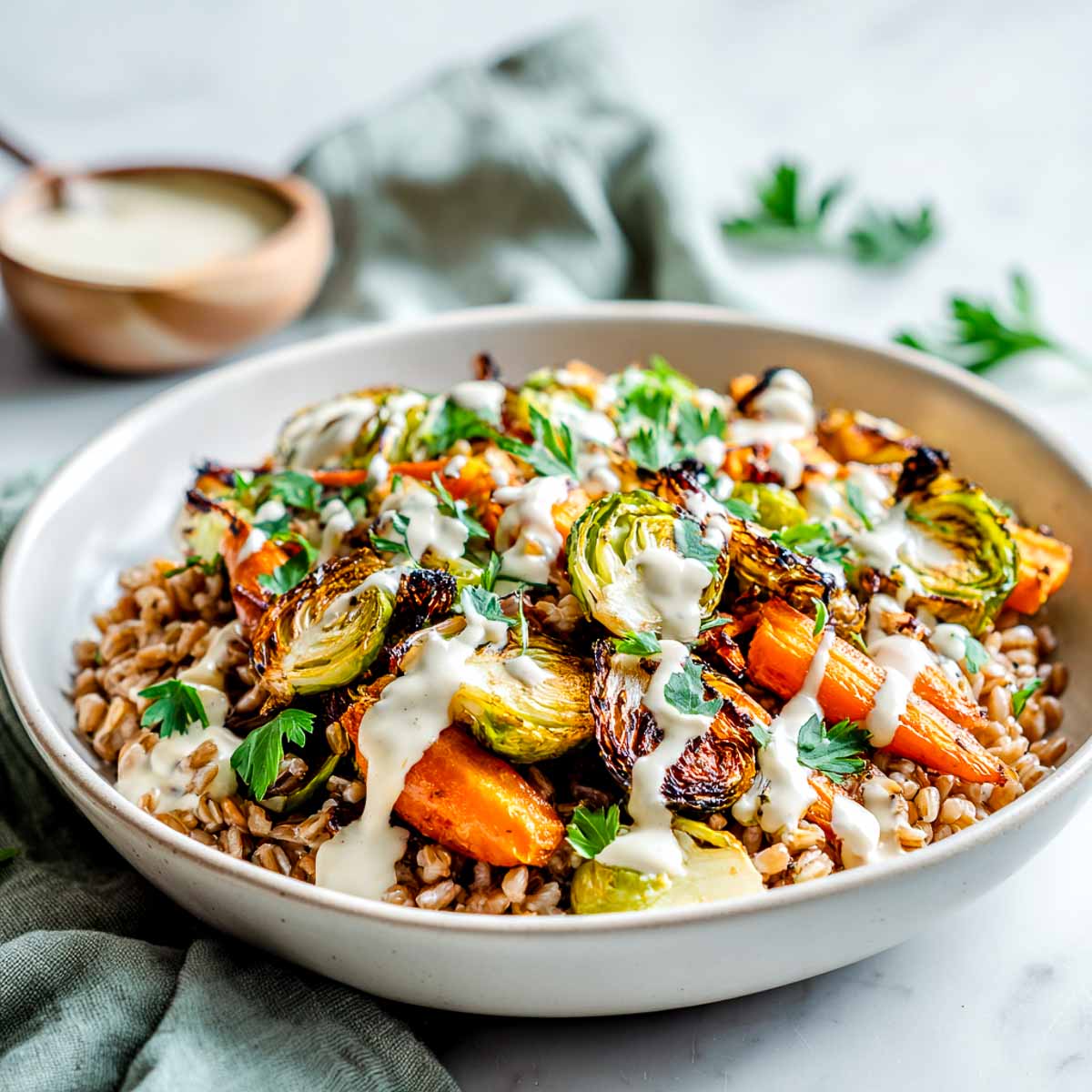 Warm farro salad with roasted carrots, Brussels sprouts, and tahini drizzle.