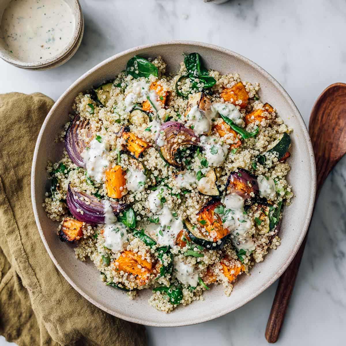 Warm quinoa salad with roasted vegetables and cottage cheese dressing in bowl.