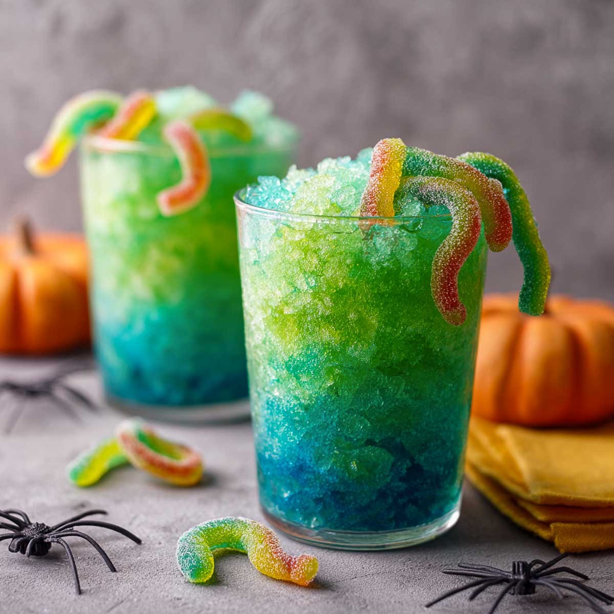 Green and blue slush Halloween drink with gummy worms crawling out.