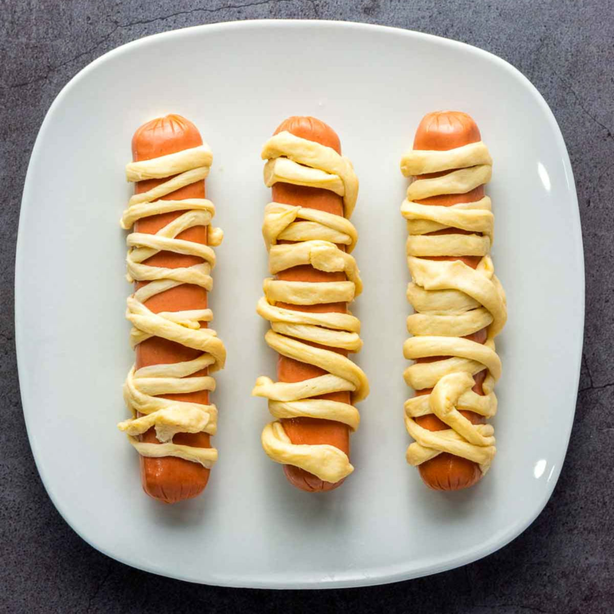 Hot dogs wrapped with crescent roll dough strips to resemble mummies.
