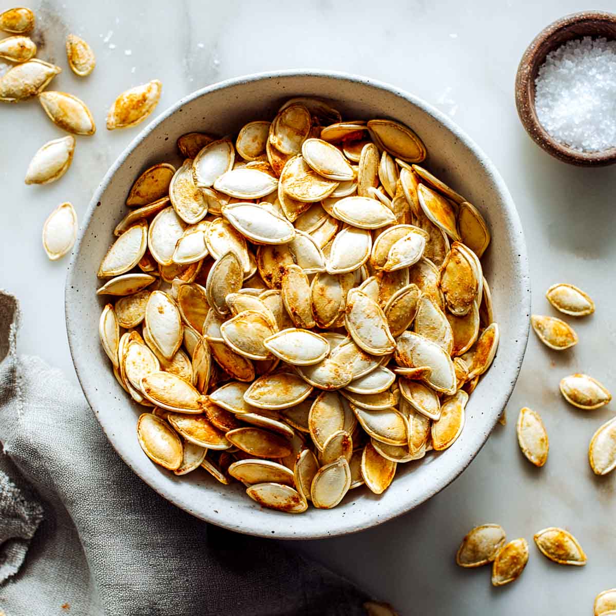 Crispy air fryer pumpkin seeds in a white bowl.
