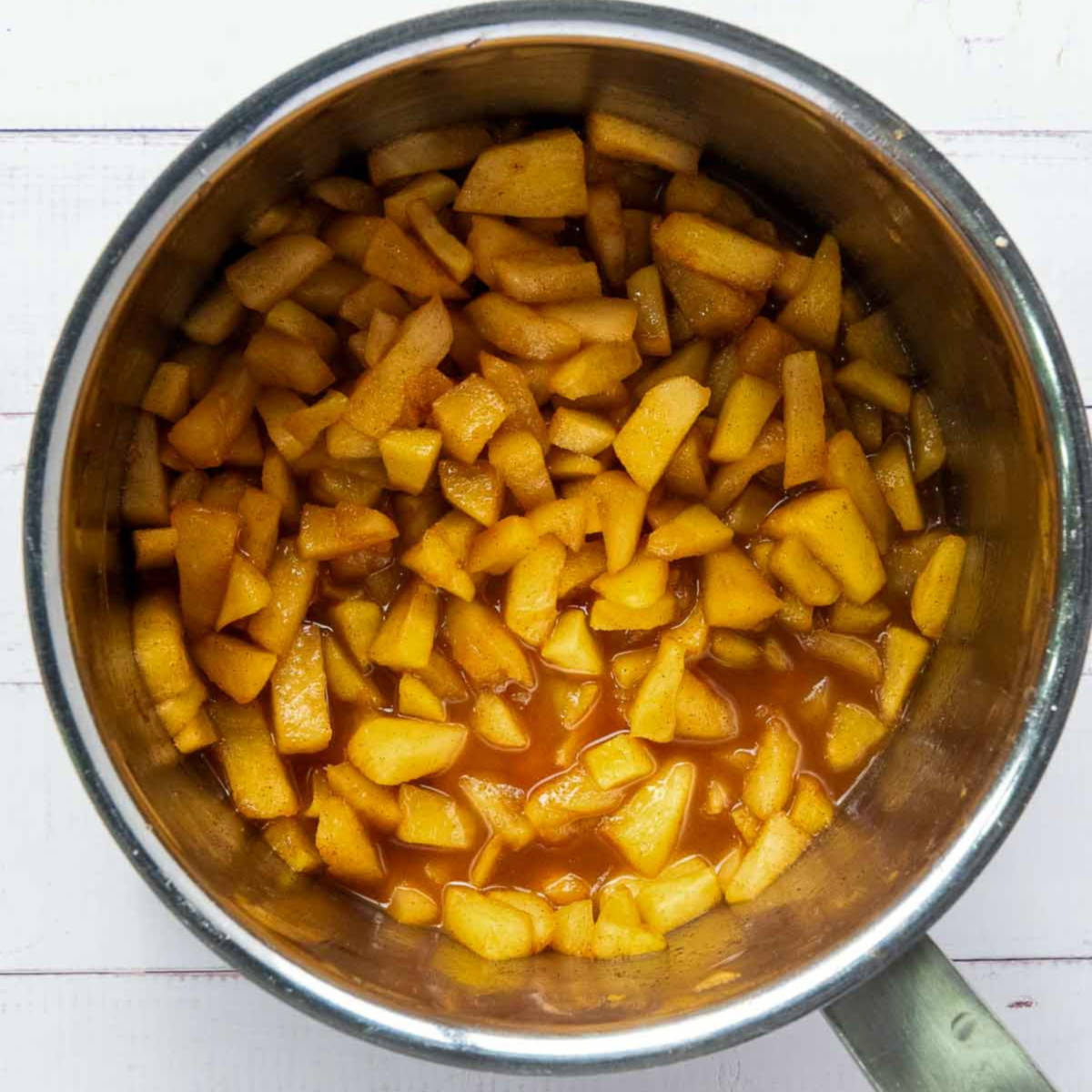 Cooked apple filling with cinnamon and sugar in a saucepan.