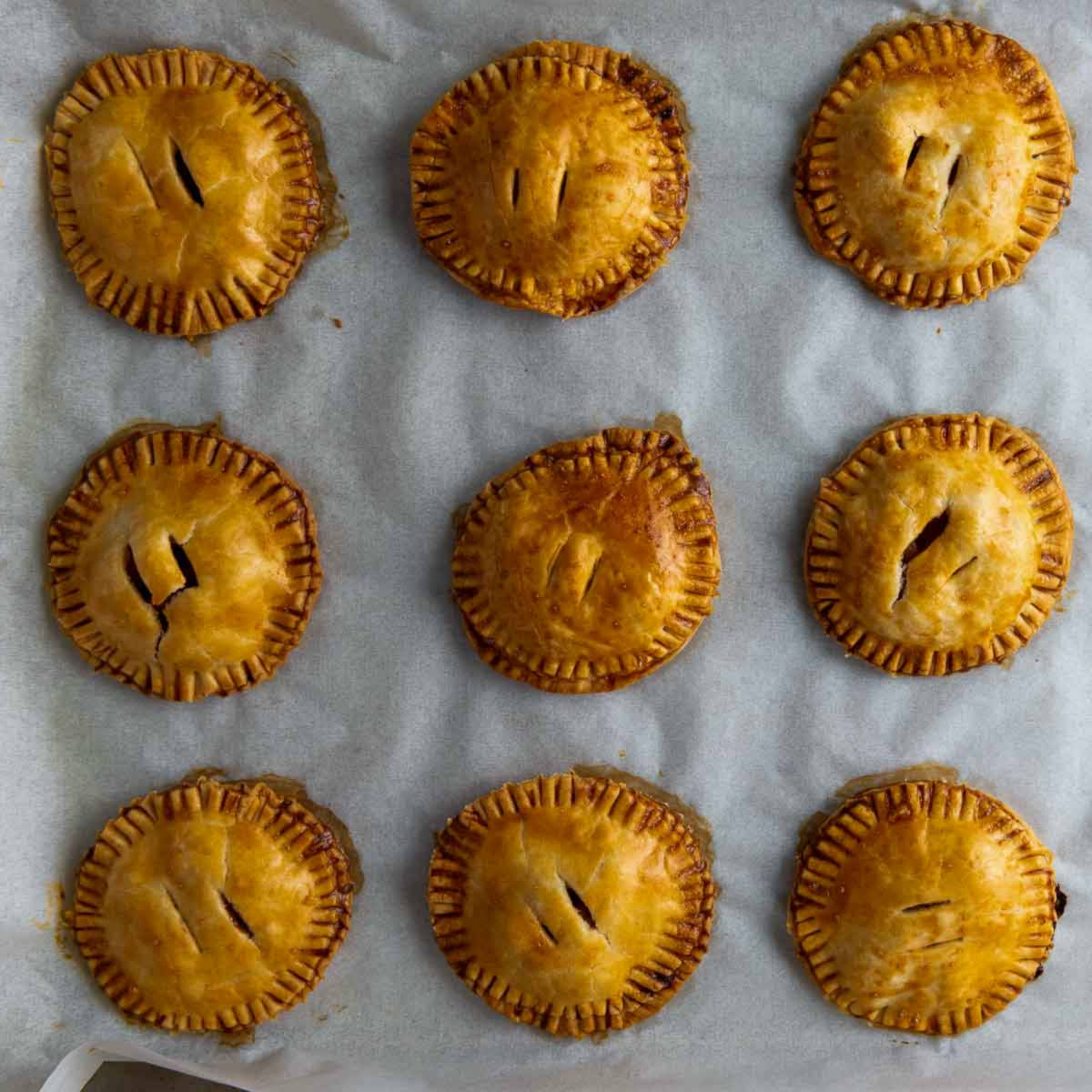Golden baked apple hand pies cooling on parchment paper.