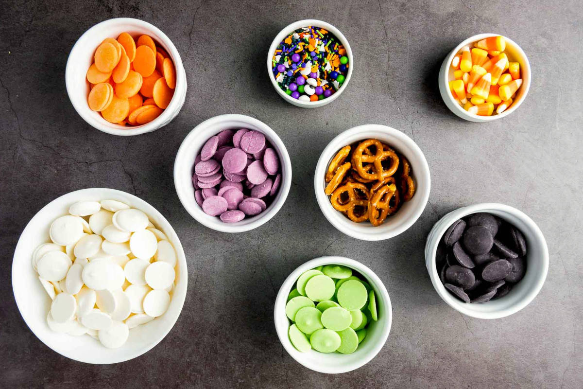 Bowls of candy melts, sprinkles, pretzels, and candy corn arranged.