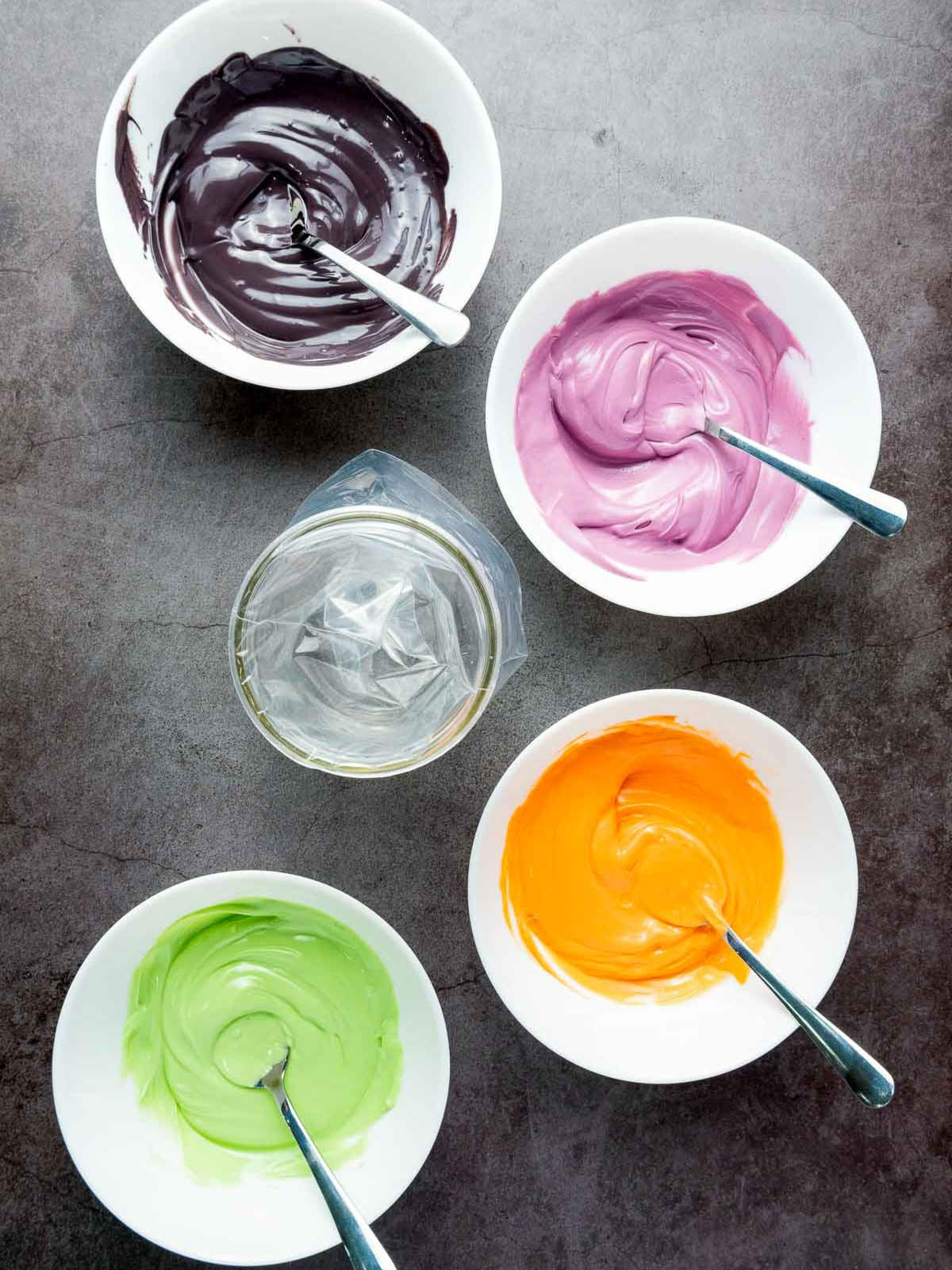 Bowls of melted candy melts in purple, orange, green, and black.