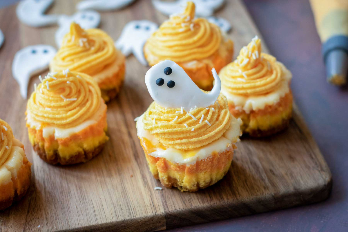 Mini candy corn cheesecake topped with orange frosting swirl and fondant ghost.
