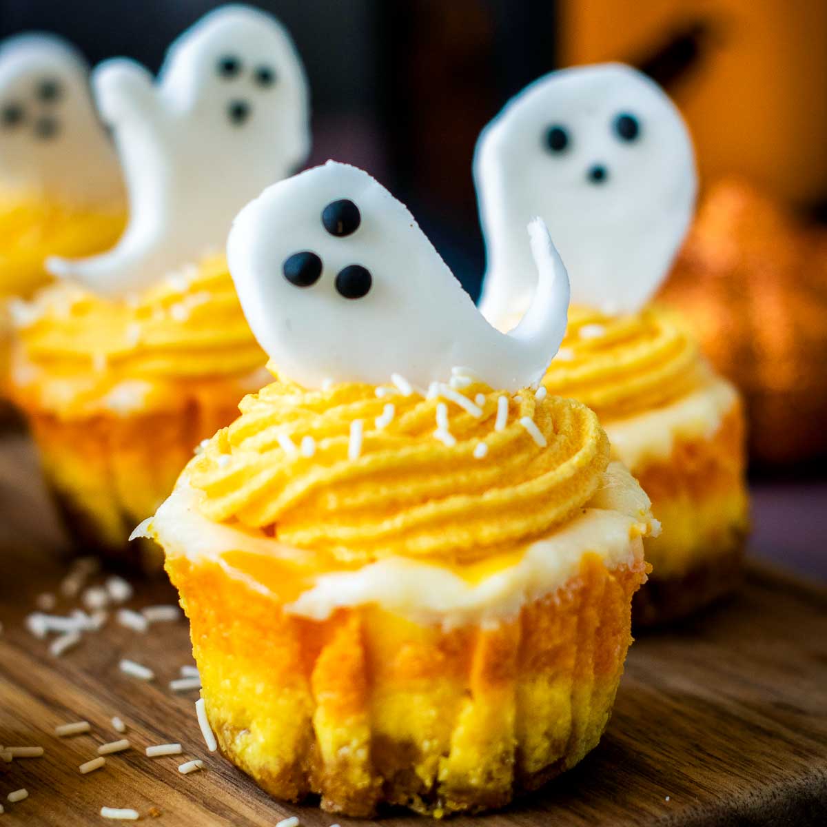 Close-up of mini candy corn cheesecake with ghost topper and white sprinkles.