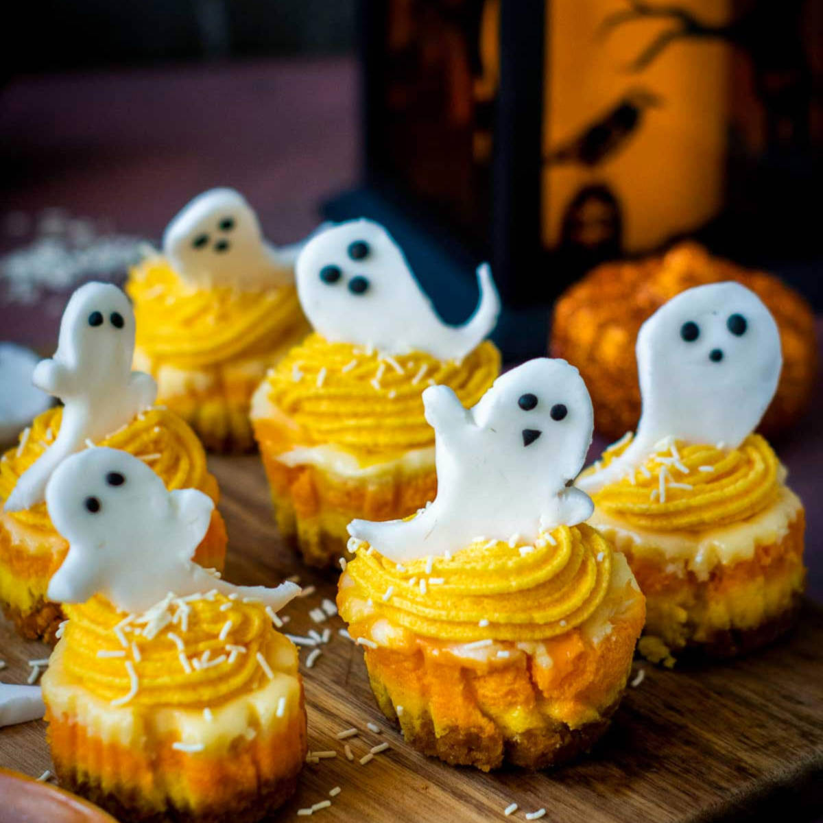 Side view of ghost-topped candy corn cheesecake on a wooden board.