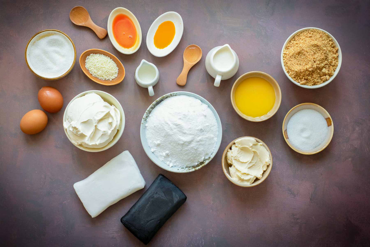 Overhead view of Halloween candy corn cheesecake ingredients arranged in bowls.