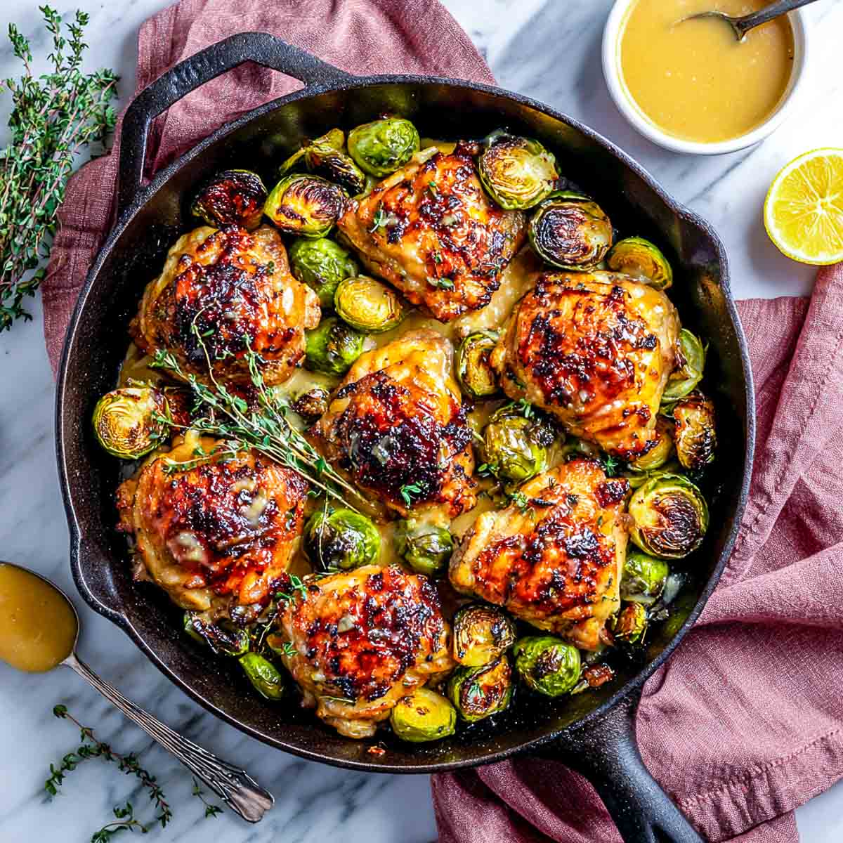 Cast iron skillet with maple Dijon glazed chicken thighs and roasted Brussels sprouts.