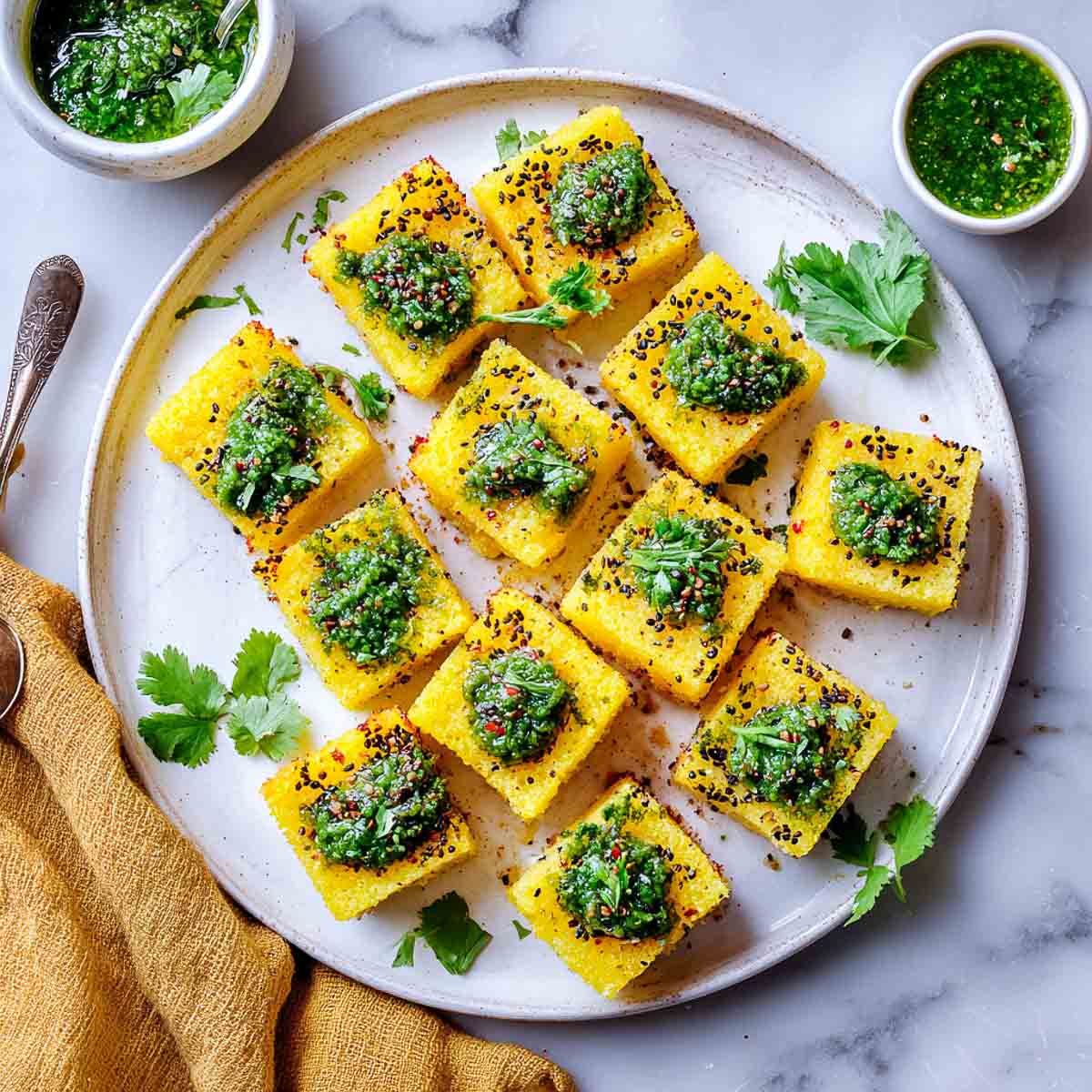 Small pieces of dhokla topped with green chutney.