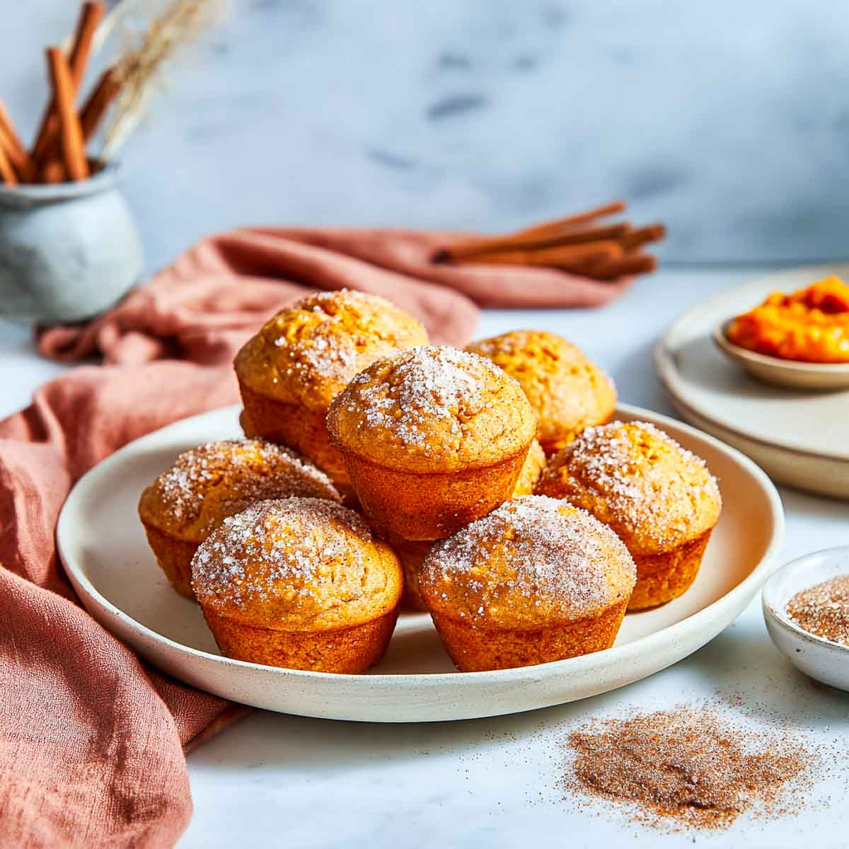 Golden pumpkin spice protein muffins with sugar topping on a cream plate.