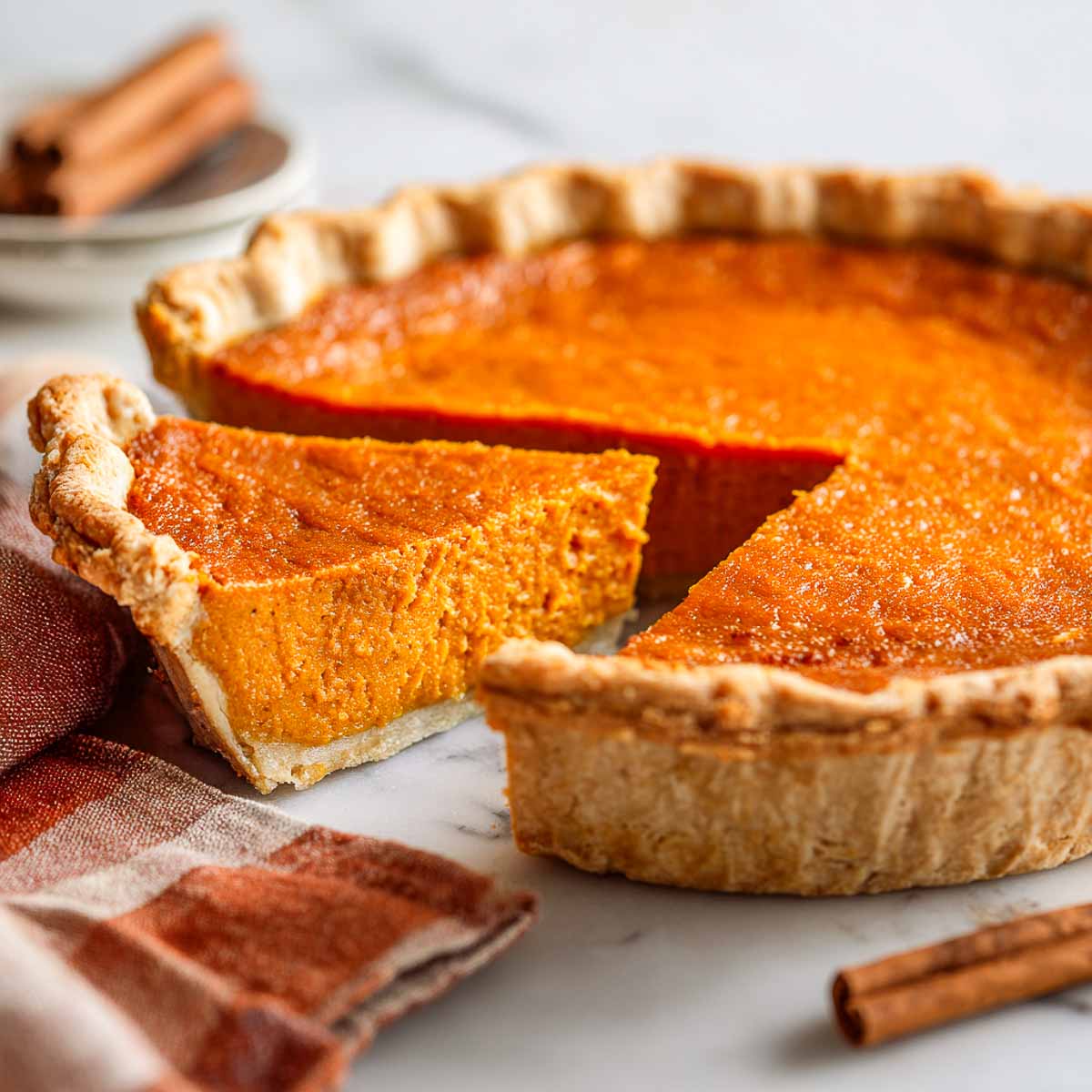 Southern sweet potato pie with a golden gluten-free crust and a clean slice cut to show the smooth orange filling.