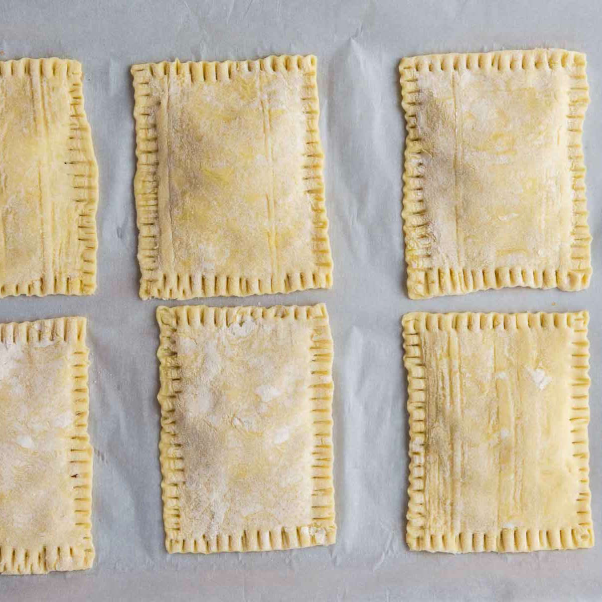 Unbaked upside down apple tarts with puff pastry sealed around the filling.