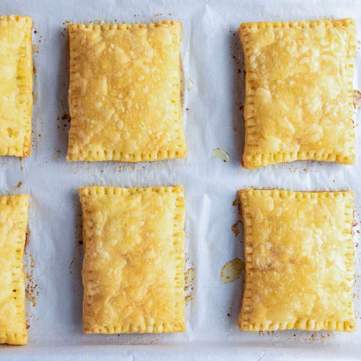 Golden baked puff pastry rectangles fresh out of the oven on parchment paper.