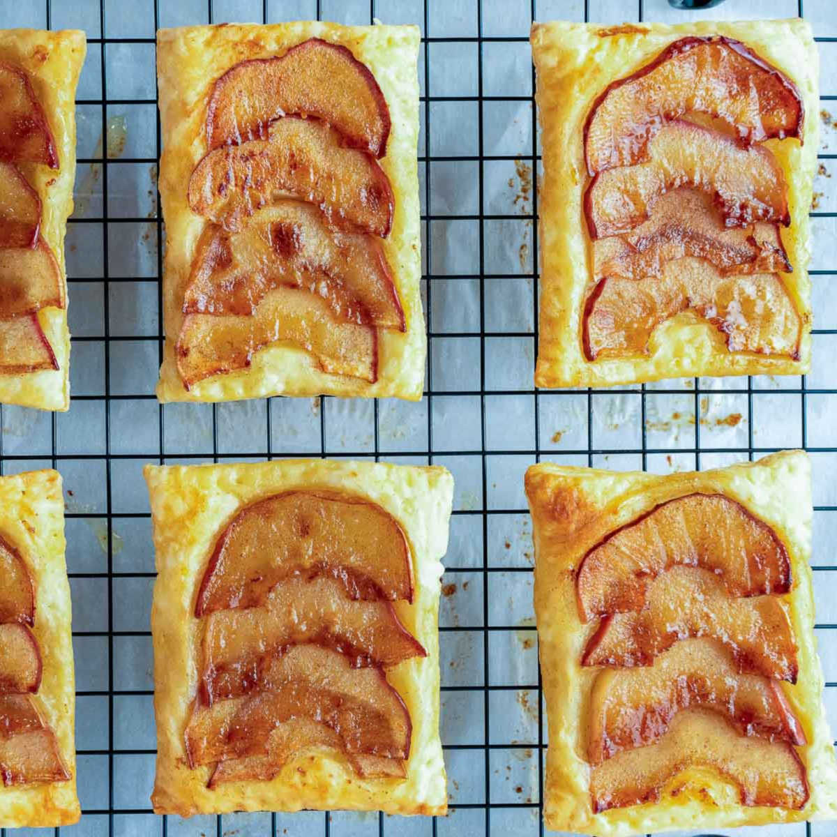 Upside down apple tarts cooling on a wire rack with caramelized apple tops showing.