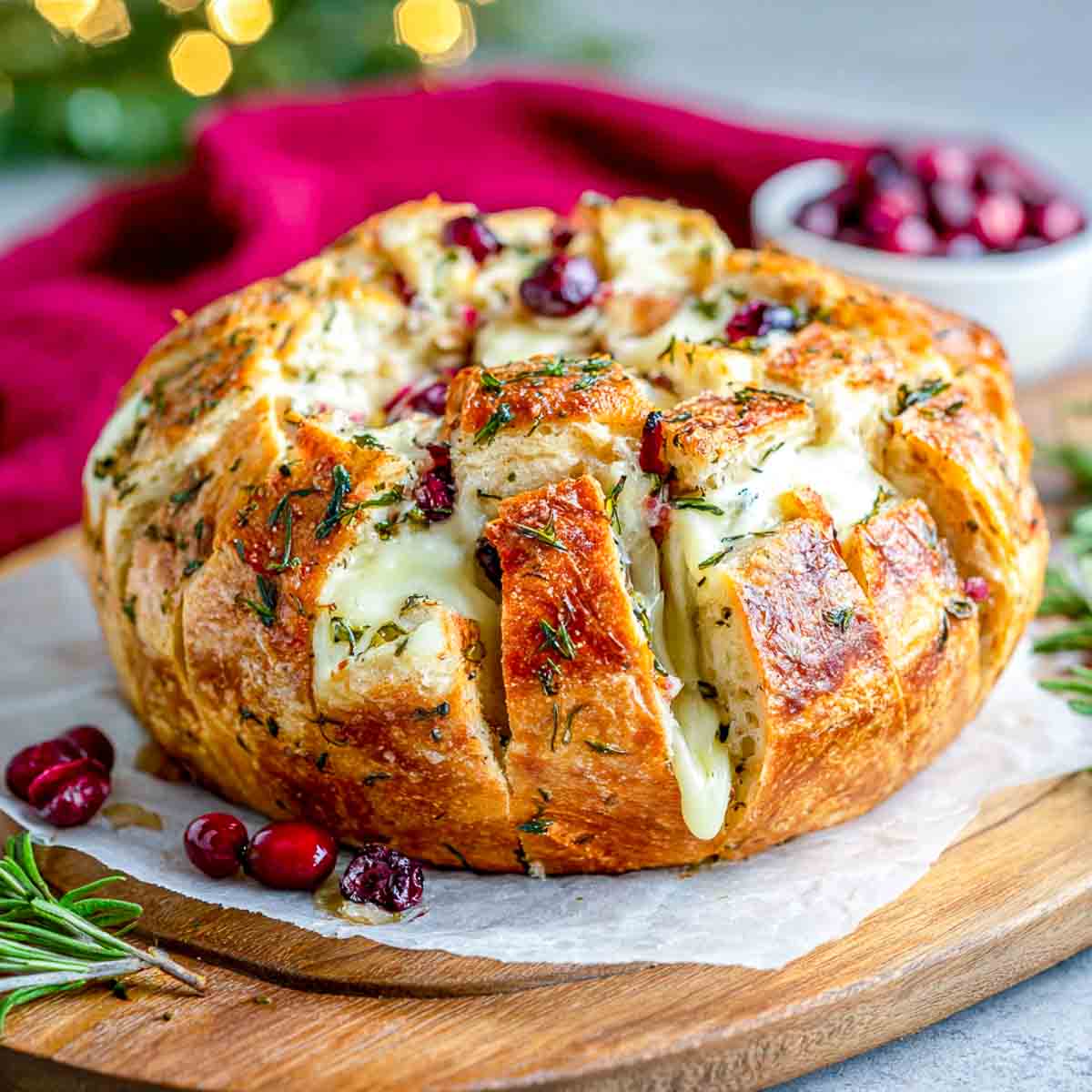 Pull-apart cranberry and brie bread on a wooden board.