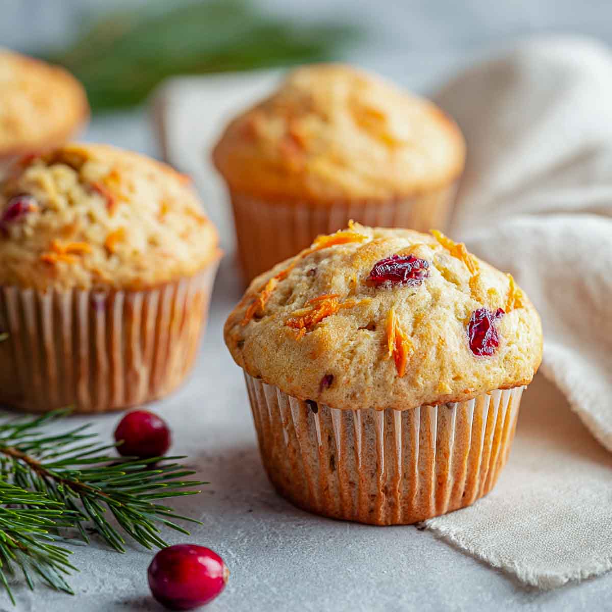 Close up of cranberry carrot muffins on a grey surface.