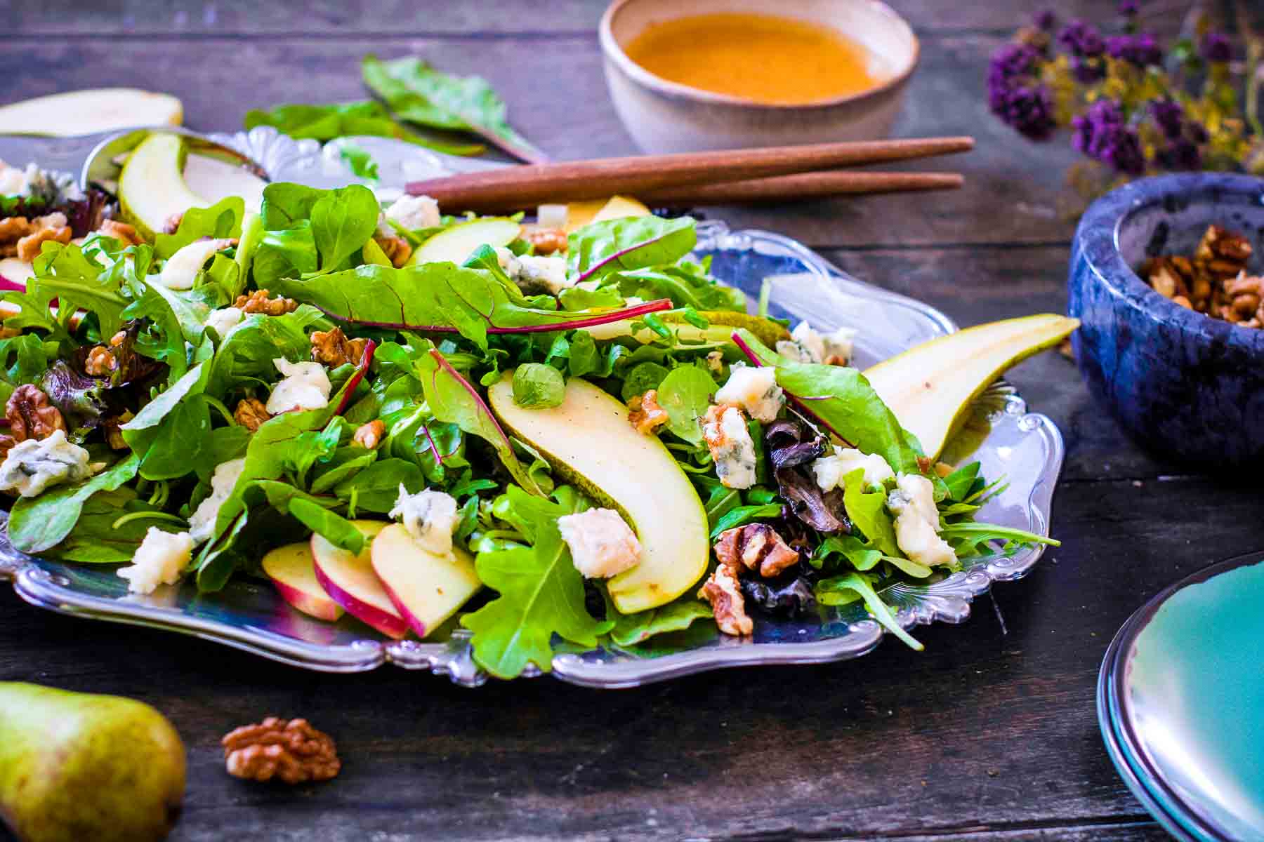 Festive harvest salad with pears, apples, walnuts, and blue cheese served on a silver platter.