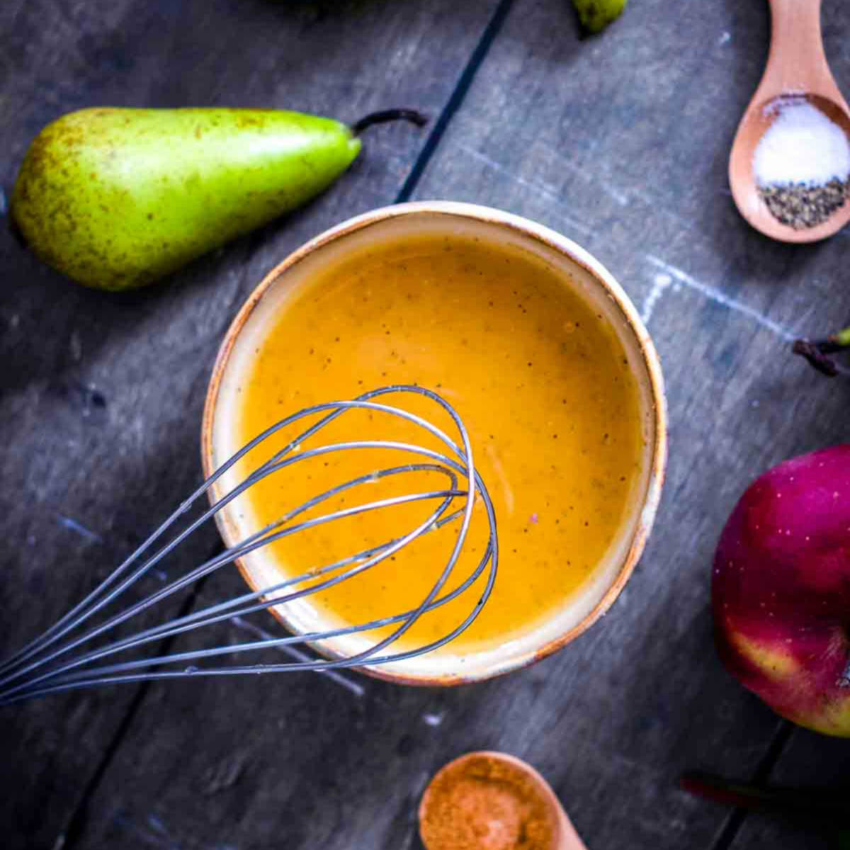 Mixing the homemade harvest salad dressing in a small bowl with fresh pears nearby.