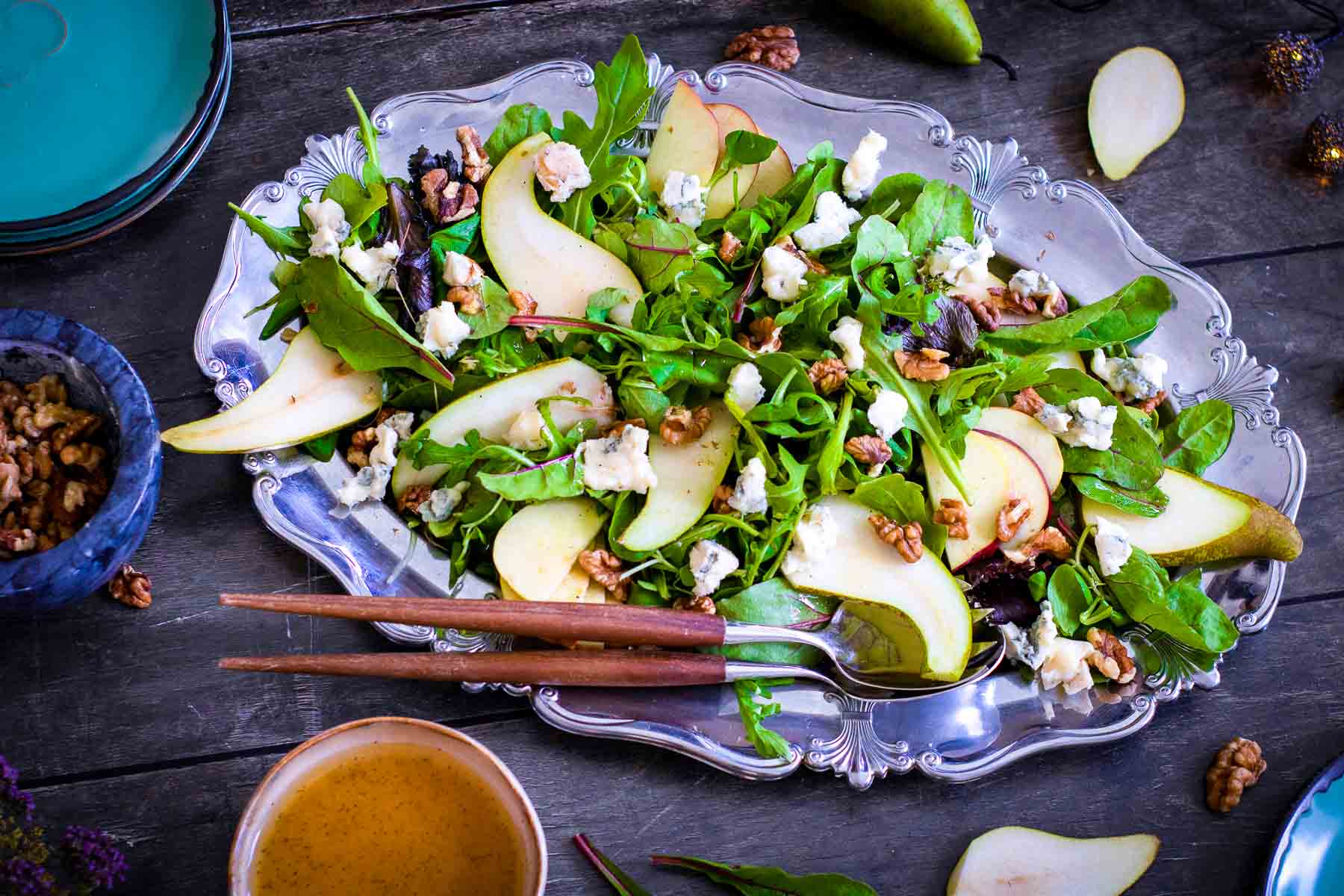 Harvest salad arranged on a platter with sliced pears, apples, walnuts, and cheese before serving.