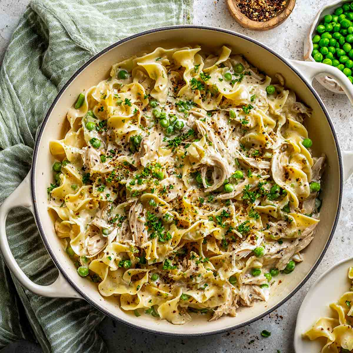 Creamy leftover turkey noodle skillet with peas and parsley in a white pan.