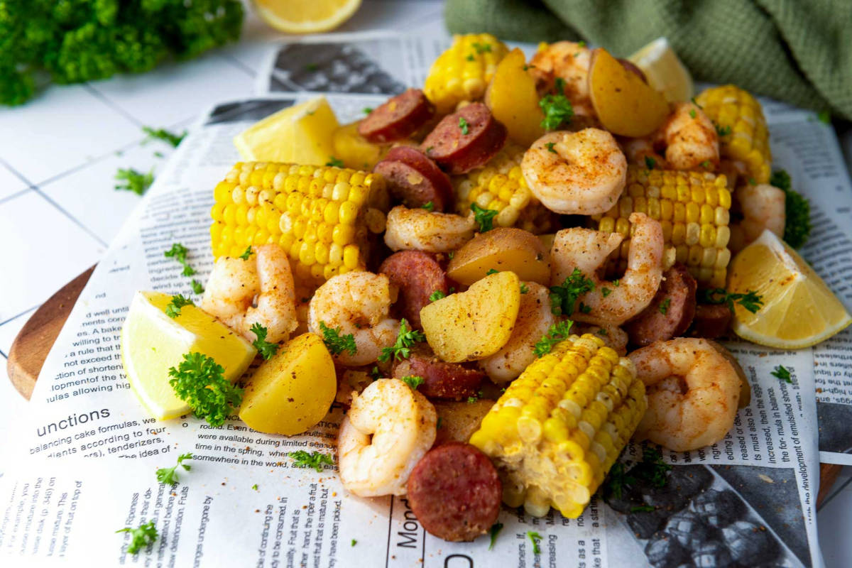 Shrimp boil served with corn, potatoes, sausage, lemon, and parsley garnish.