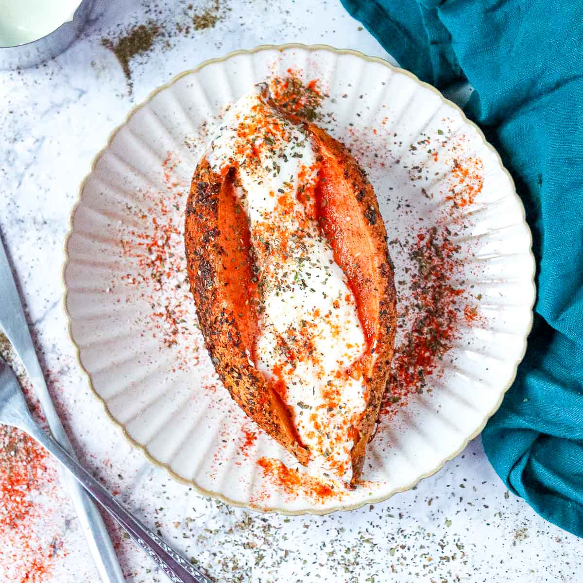 Sweet potato with yogurt drizzle on a white plate.