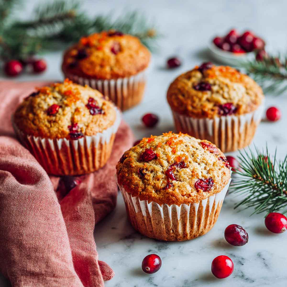 Vegan orange cranberry muffins with flaxseeds on a marble surface.