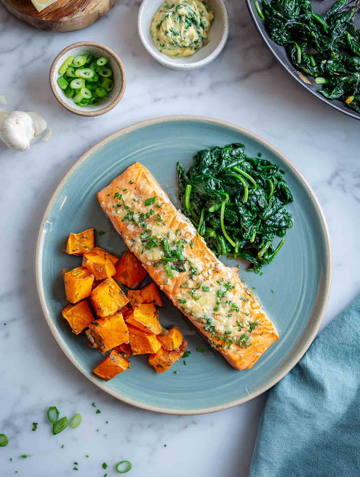 Garlic-herb butter salmon with roasted sweet potatoes and sautéed spinach.