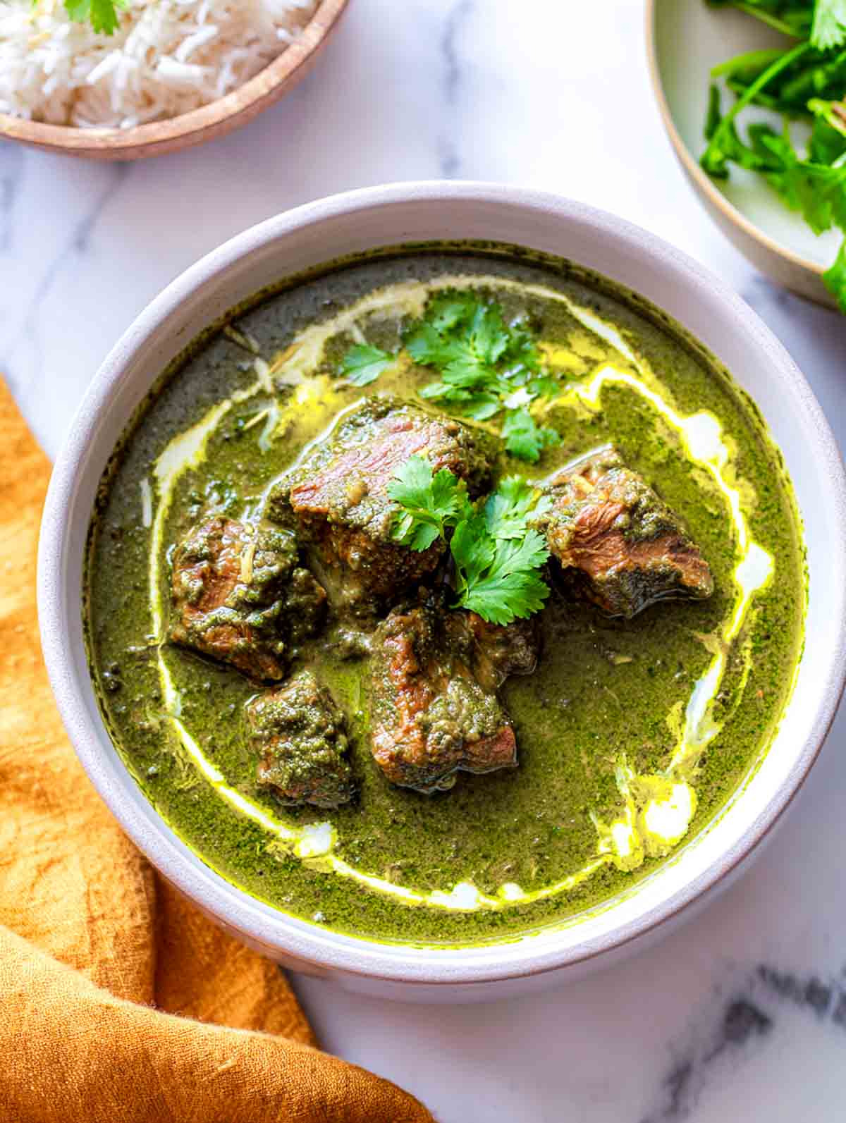 Top view of Lamb Palak in a white bowl with cilantro garnish.