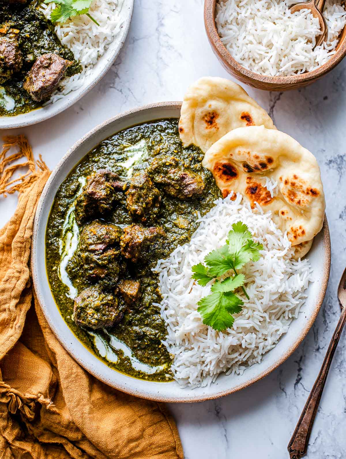 Lamb Palak plated with basmati rice and naan on a white plate.