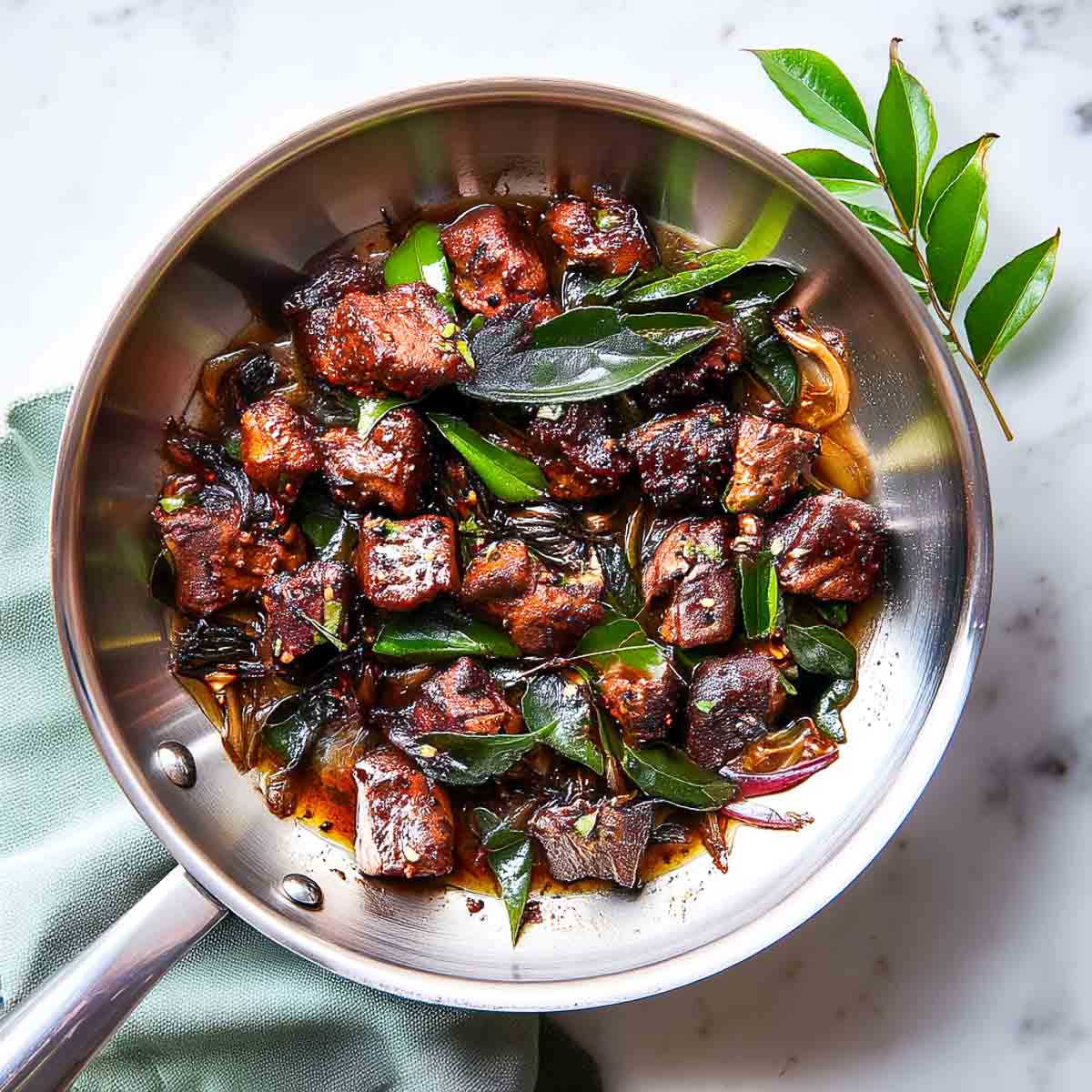 Lamb cooking down with pepper and curry leaves until dry and crisp.