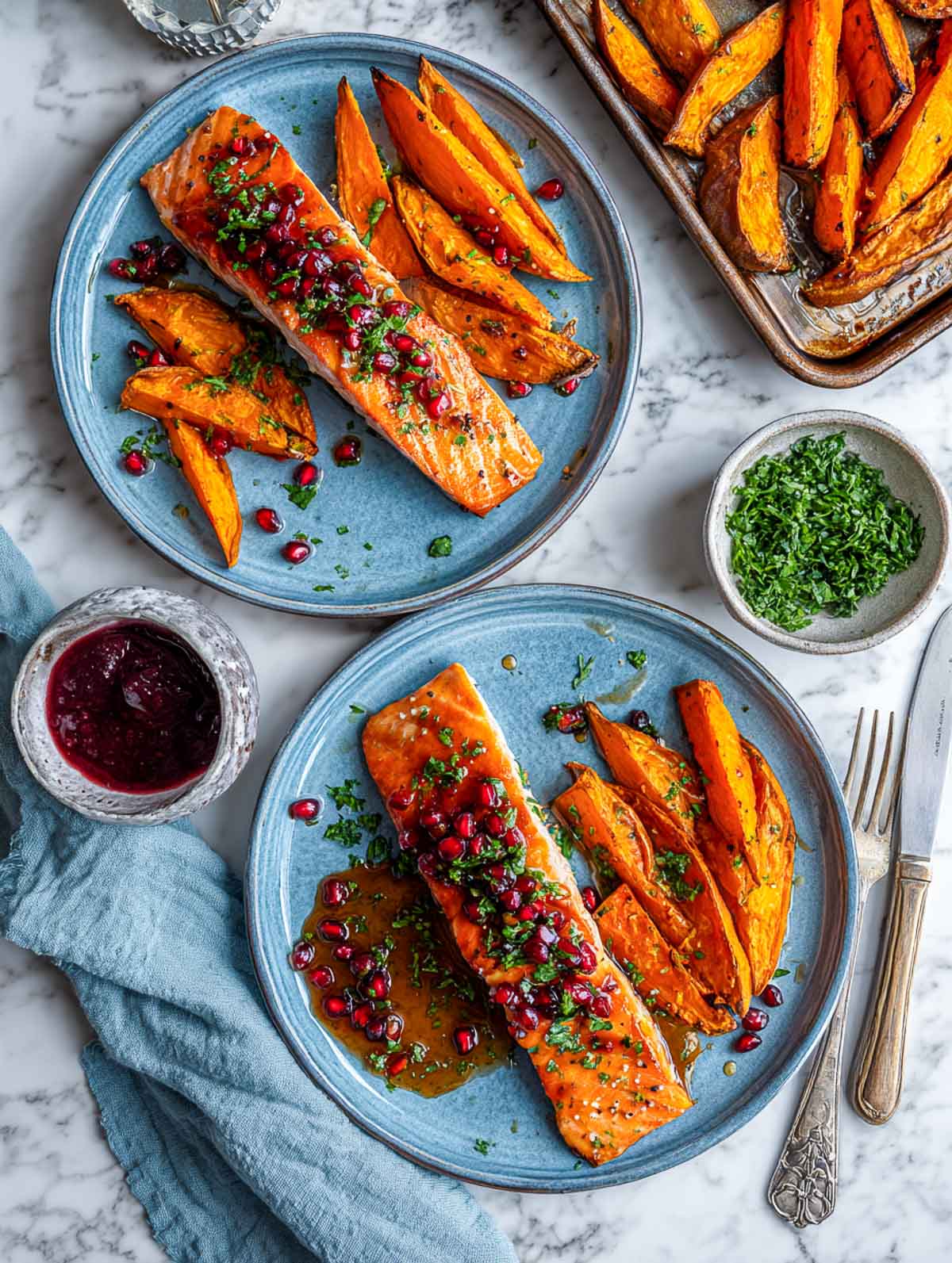 Top down view of pomegranate baked salmon with roasted sweet potato wedges.