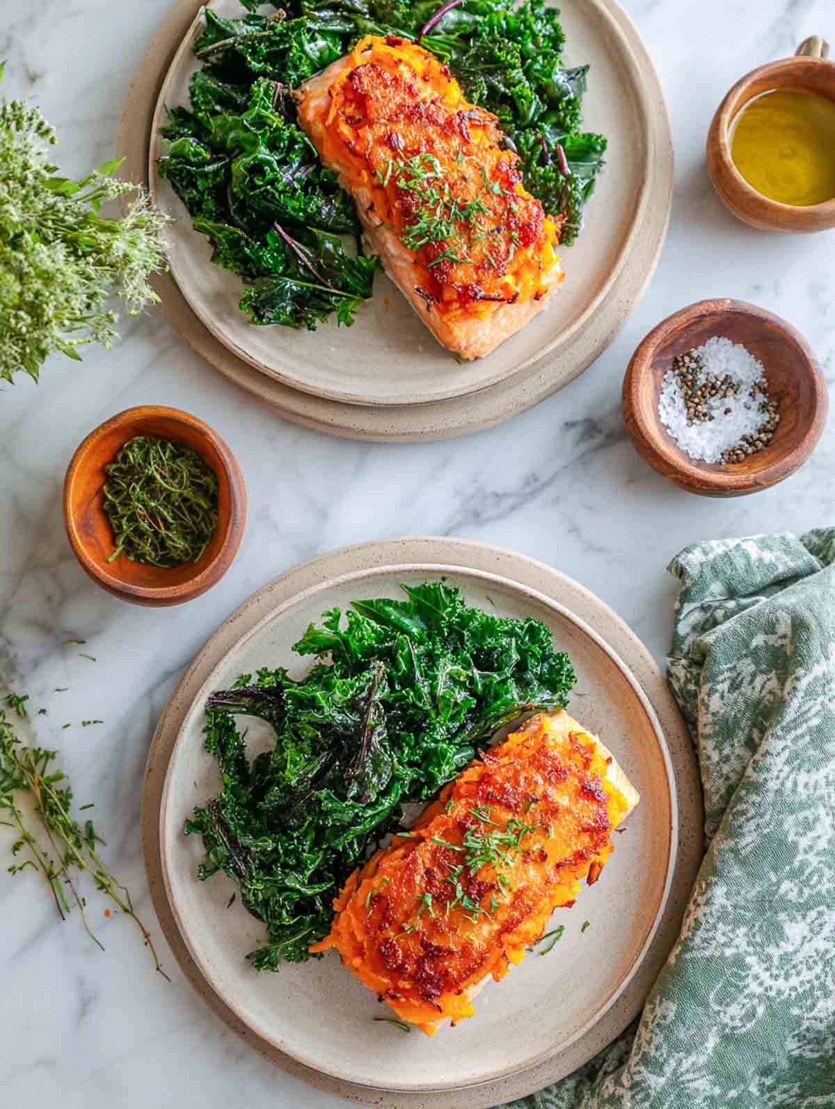 Sweet potato–crusted salmon fillets with sautéed winter greens on ceramic plates.