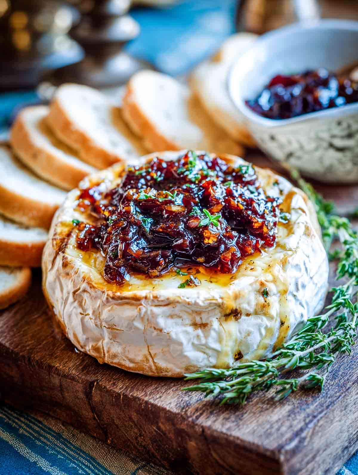 Baked brie topped with fig jam on a wooden board with bread slices.